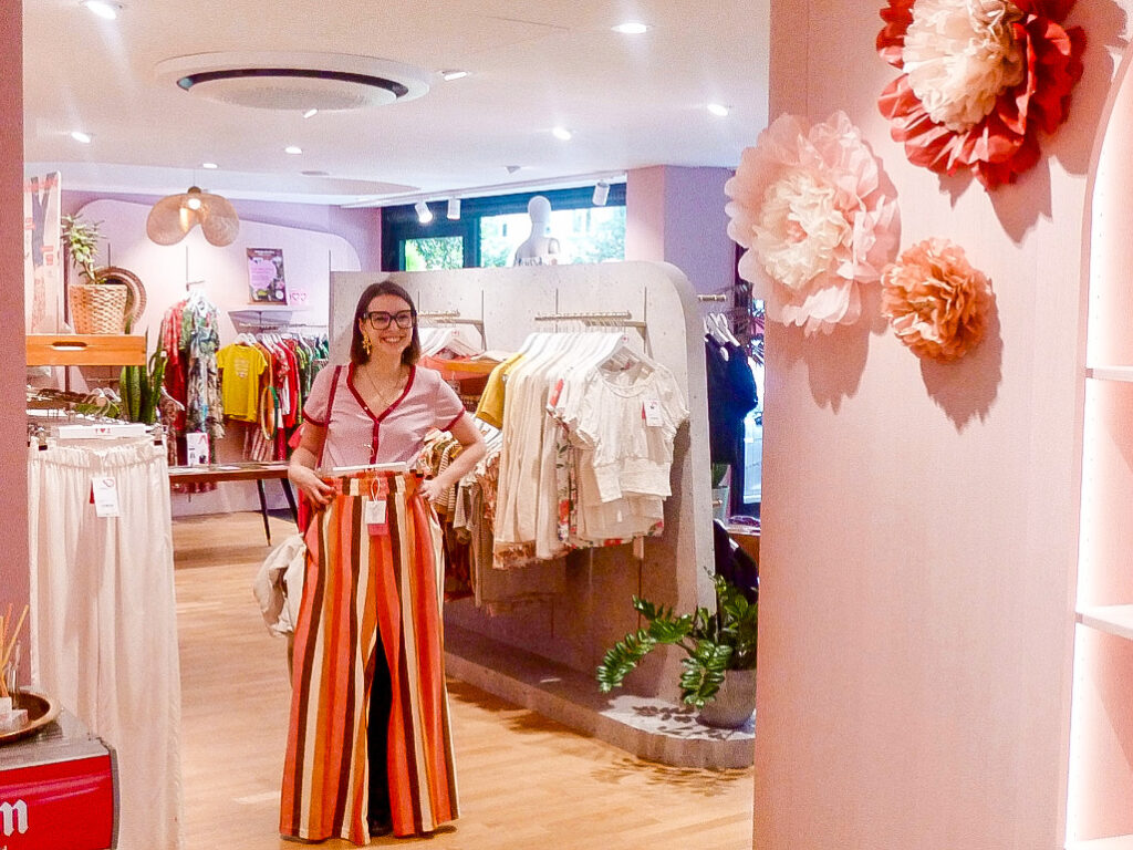 Shoppingtour: Tamina Orenda betrachtet sich mit einer neuen Hose im Spiegel eines Modegeschäfts